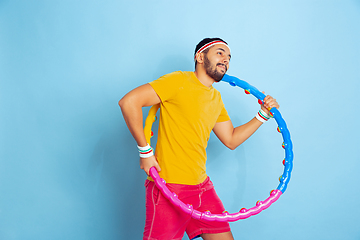 Image showing Young caucasian man in bright clothes training on blue background