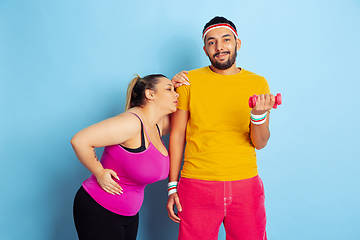 Image showing Young pretty caucasian couple in bright clothes training on blue background