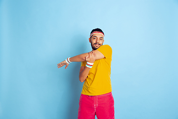 Image showing Young caucasian man in bright clothes training on blue background