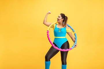 Image showing Young caucasian plus size female model\'s training on yellow background