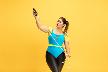 Image showing Young caucasian plus size female model\'s training on yellow background