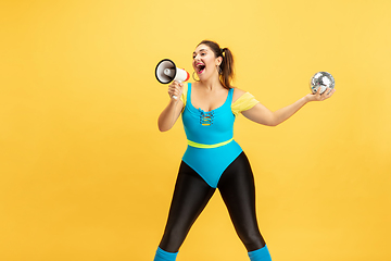 Image showing Young caucasian plus size female model\'s training on yellow background