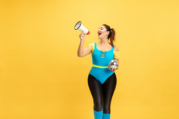 Image showing Young caucasian plus size female model\'s training on yellow background