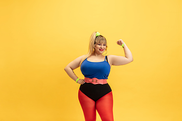 Image showing Young caucasian plus size female model\'s training on yellow background