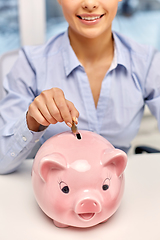 Image showing businesswoman with piggy bank and coin at office