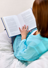 Image showing close up of woman reading book sitting on sofa