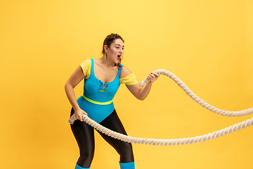 Image showing Young caucasian plus size female model\'s training on yellow background