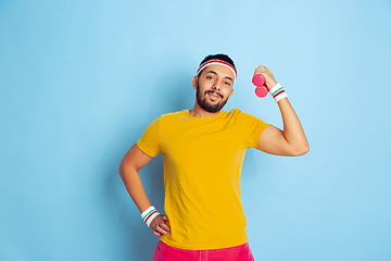 Image showing Young caucasian man in bright clothes training on blue background