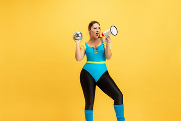 Image showing Young caucasian plus size female model\'s training on yellow background