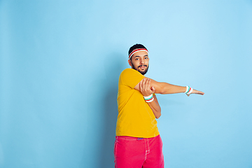 Image showing Young caucasian man in bright clothes training on blue background