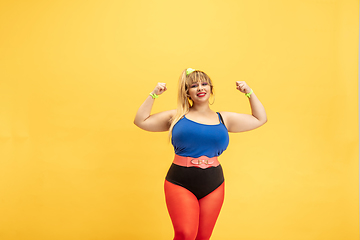 Image showing Young caucasian plus size female model\'s training on yellow background