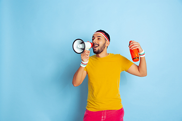 Image showing Young caucasian man in bright clothes training on blue background