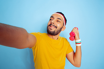 Image showing Young caucasian man in bright clothes training on blue background