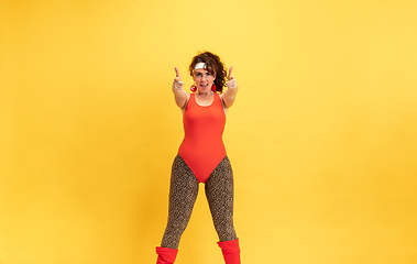 Image showing Young caucasian plus size female model\'s training on yellow background