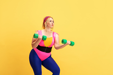 Image showing Young caucasian plus size female model\'s training on yellow background