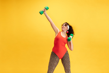 Image showing Young caucasian plus size female model\'s training on yellow background