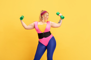 Image showing Young caucasian plus size female model\'s training on yellow background