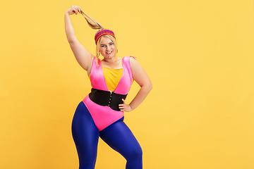 Image showing Young caucasian plus size female model\'s training on yellow background