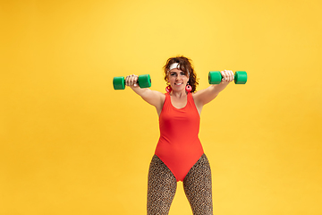 Image showing Young caucasian plus size female model\'s training on yellow background