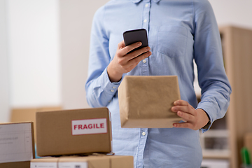 Image showing woman with smartphone and parcels at post office