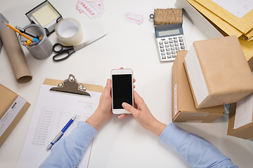 Image showing hands with smartphone and parcels at post office