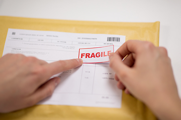 Image showing hands sticking fragile marks to parcel in envelope