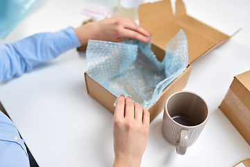 Image showing hands packing mug to parcel box at post office