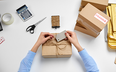 Image showing hands tying name tag to parcel box at post office