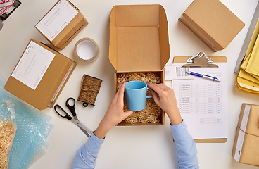 Image showing hands packing mug to parcel box at post office