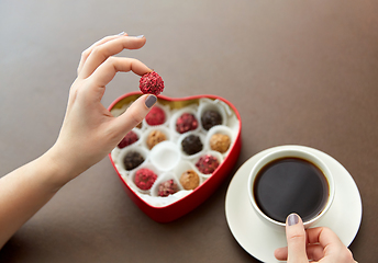 Image showing hands, candies in heart shaped box and coffee cup