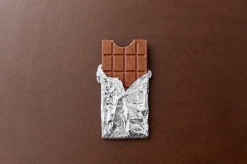 Image showing chocolate bar in foil wrapper on brown background