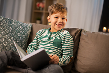 Image showing happy smiling little boy reading book at home