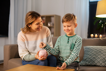 Image showing mother and little son with piggy bank at home