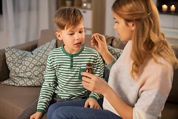 Image showing mother giving medication or cough syrup to ill son