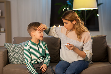 Image showing sad mother with thermometer and ill son at home