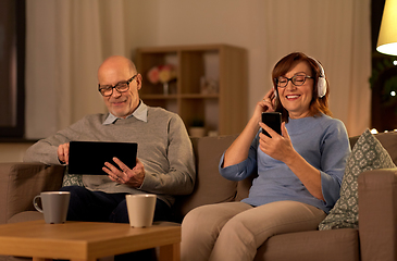Image showing happy senior couple with gadgets at home