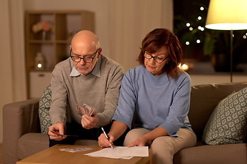 Image showing senior couple with bills counting money at home