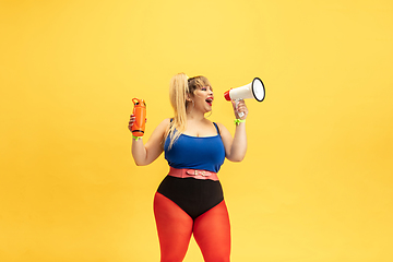 Image showing Young caucasian plus size female model\'s training on yellow background