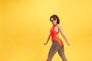 Image showing Young caucasian plus size female model\'s training on yellow background