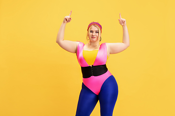 Image showing Young caucasian plus size female model\'s training on yellow background