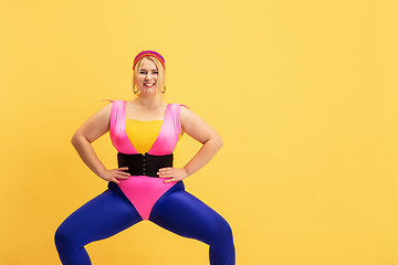 Image showing Young caucasian plus size female model\'s training on yellow background