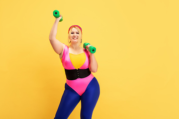 Image showing Young caucasian plus size female model\'s training on yellow background