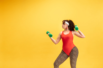 Image showing Young caucasian plus size female model\'s training on yellow background