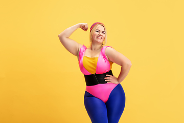 Image showing Young caucasian plus size female model\'s training on yellow background