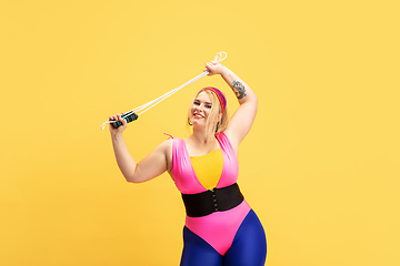 Image showing Young caucasian plus size female model\'s training on yellow background