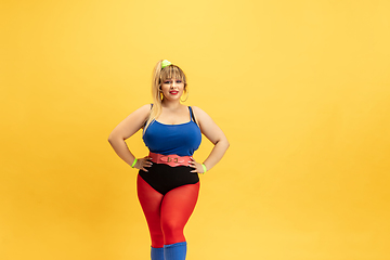 Image showing Young caucasian plus size female model\'s training on yellow background