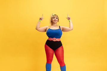 Image showing Young caucasian plus size female model\'s training on yellow background