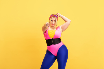 Image showing Young caucasian plus size female model\'s training on yellow background