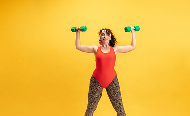 Image showing Young caucasian plus size female model\'s training on yellow background