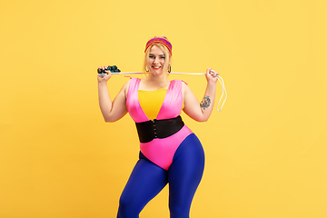 Image showing Young caucasian plus size female model\'s training on yellow background